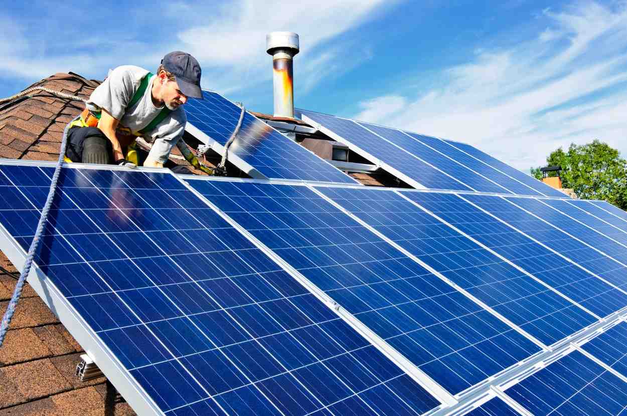 Technician installing rooftop solar panels, representing energy-efficient solar power solutions and industry expertise.
