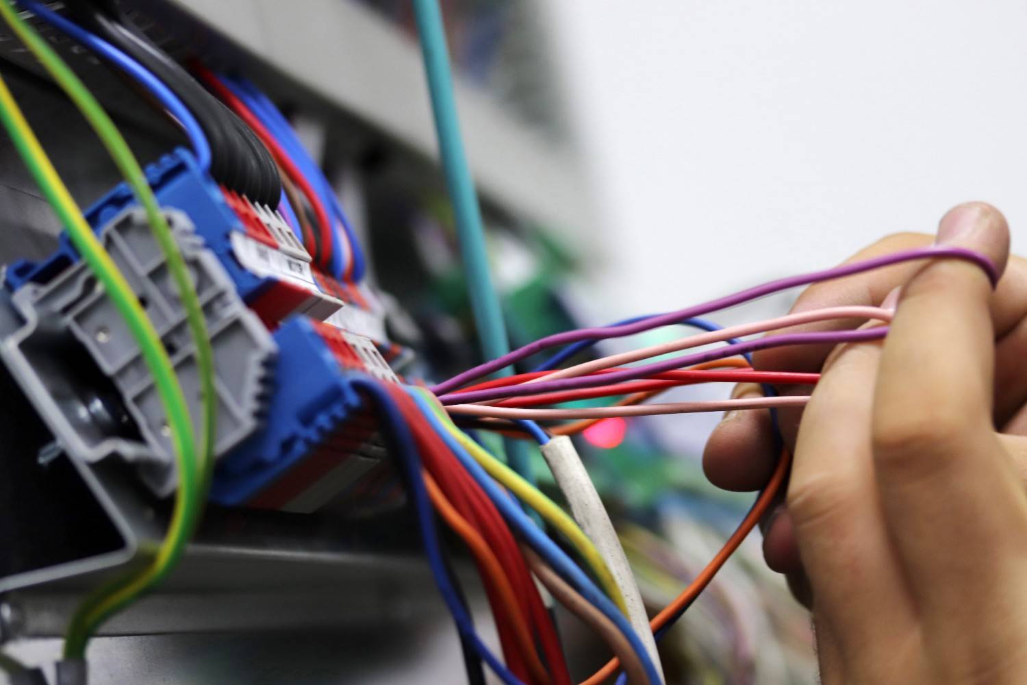 Electrician organizing color-coded wire connections for a clean, code-compliant electrical panel install.
